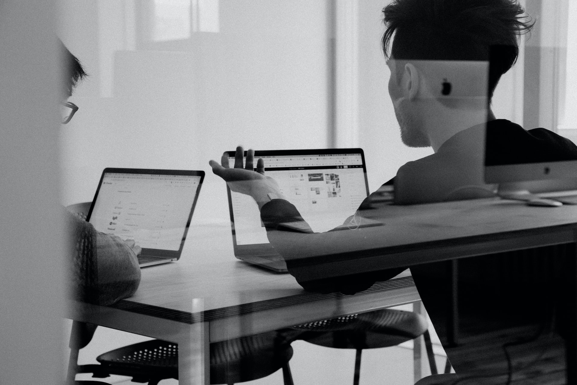 2 people being looked on through a piece of glass who are working on their laptops